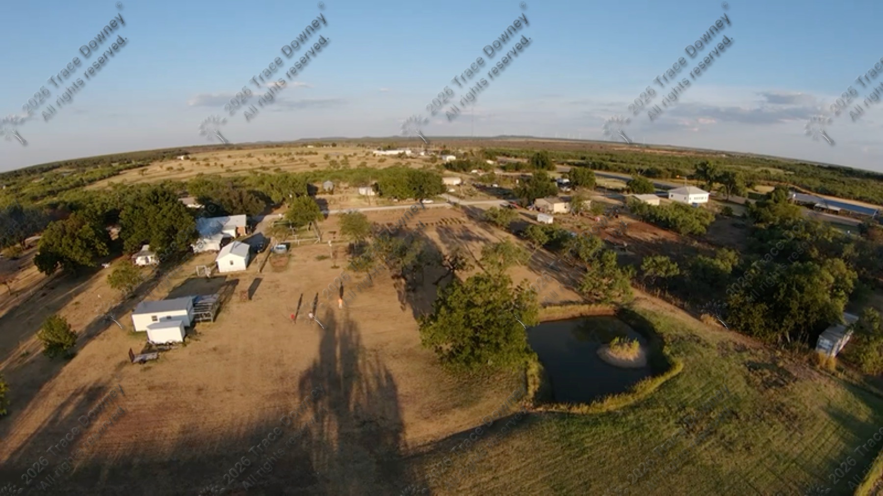 Raw drone still showing a rural property and surrounding land from above.