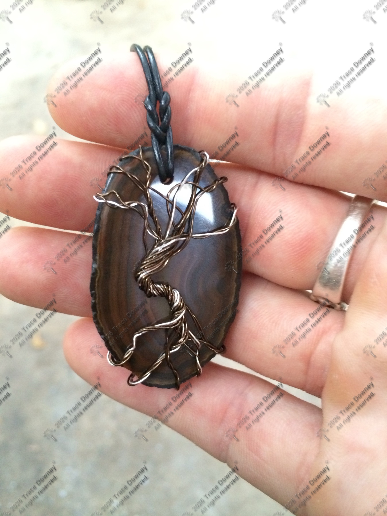Dark agate pendant held in a hand with wire wrapping around the stone.