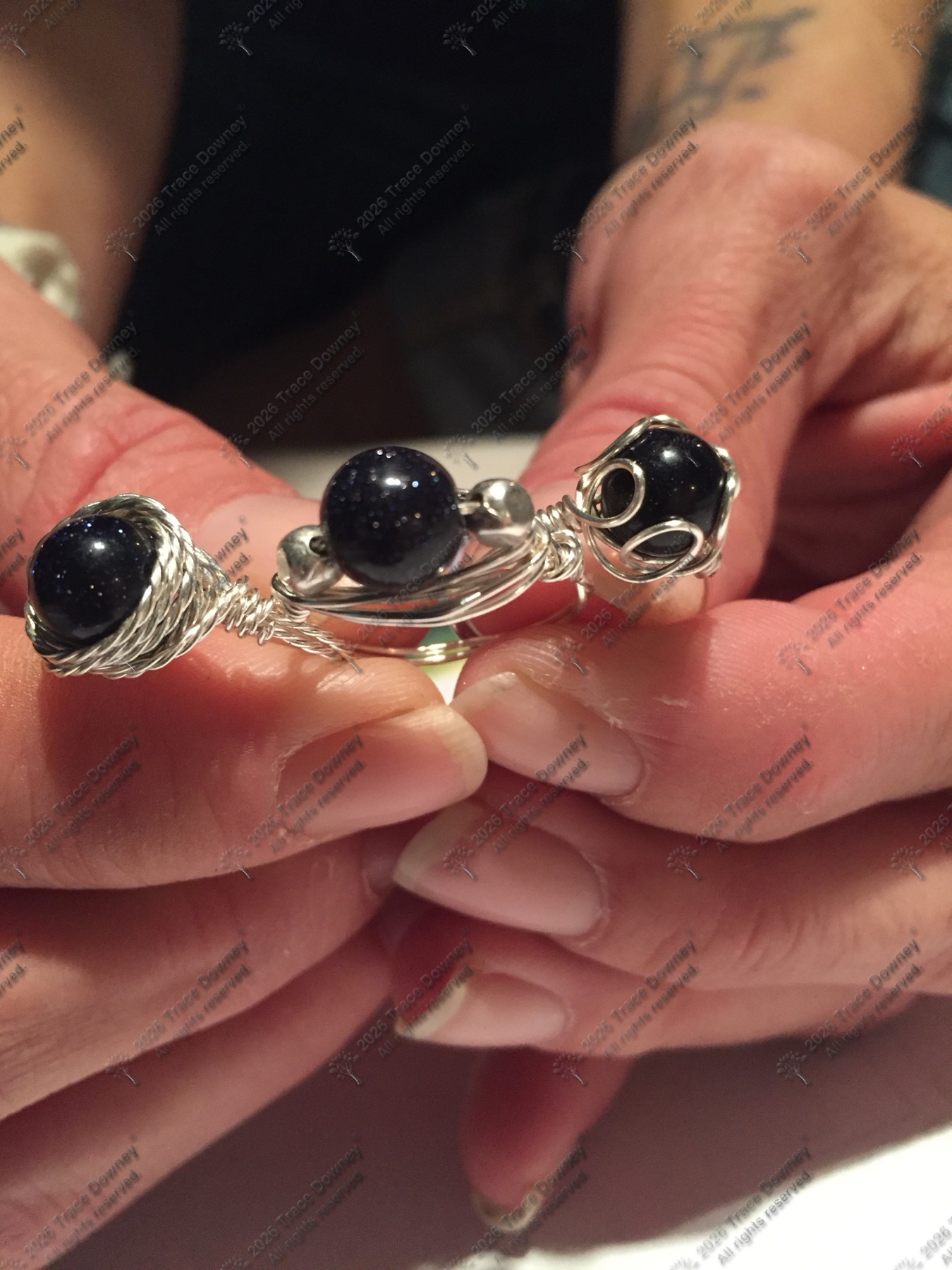Close view of dark stone rings being held between both hands.