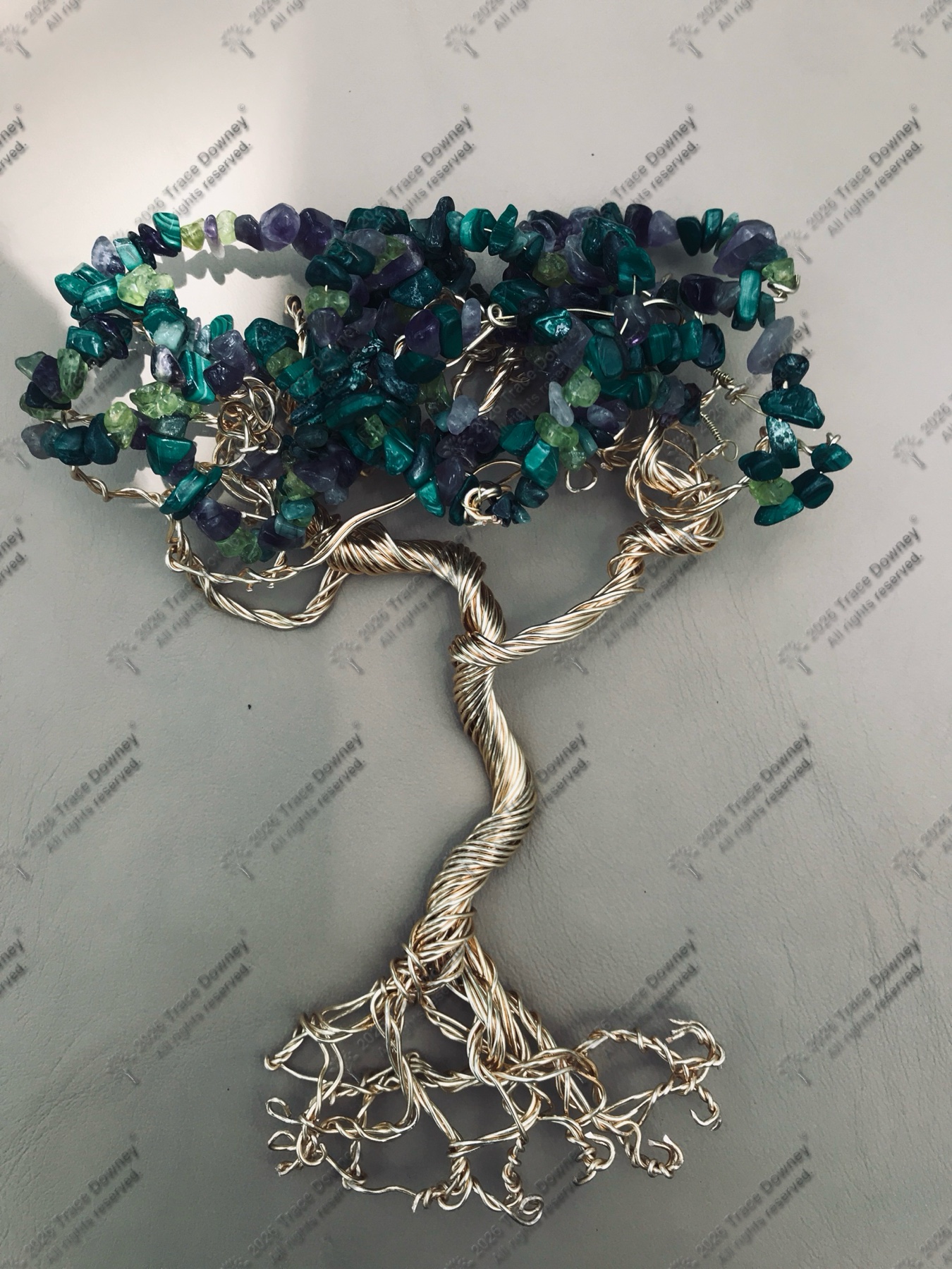 Turquoise and purple stone wire tree mounted on a wall.