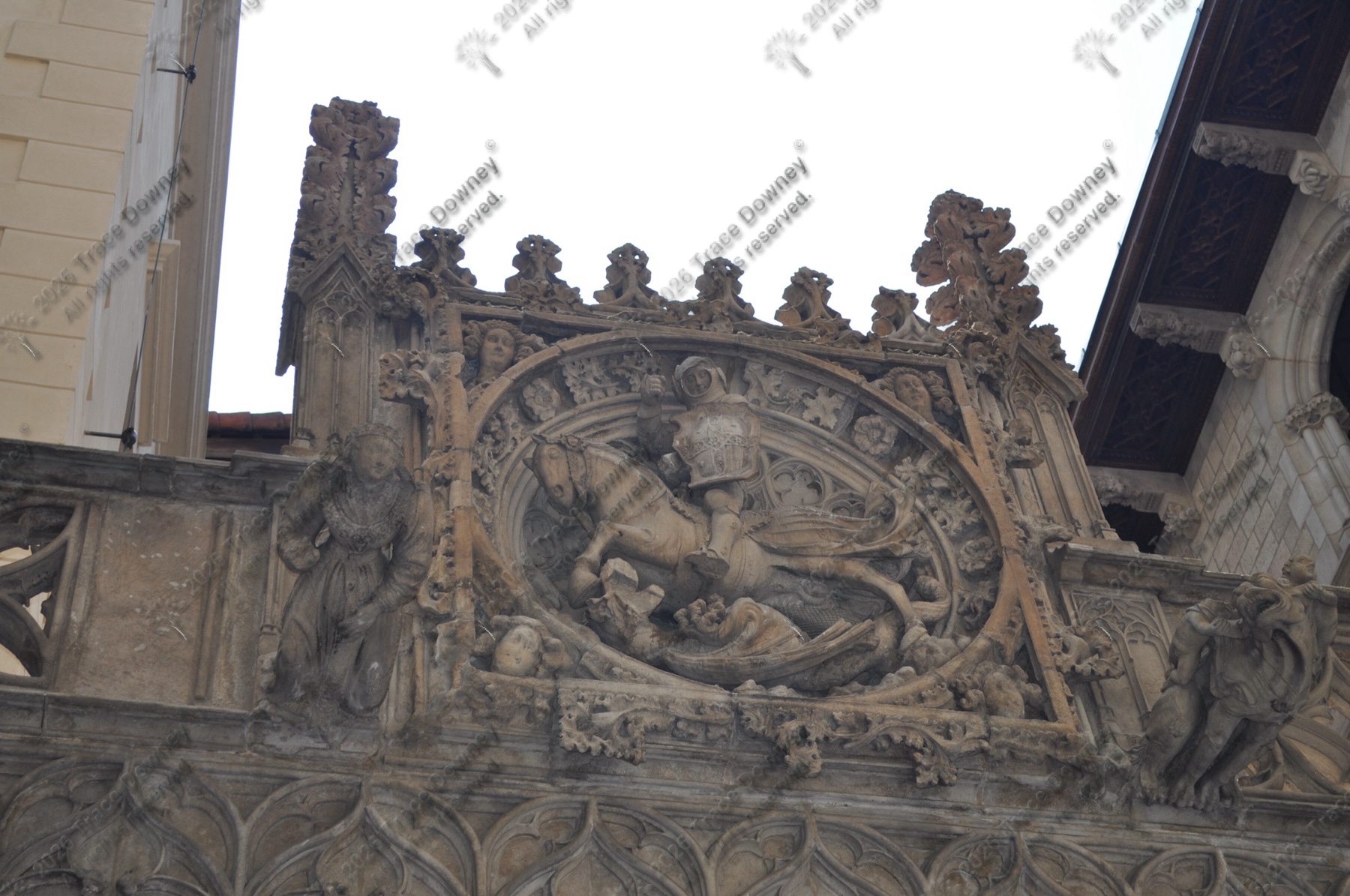 Carved stone crest and figures on an ornate historic facade.