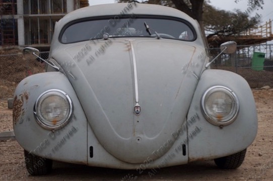 Close study of the front of a vintage Volkswagen with bold color and chrome detail.