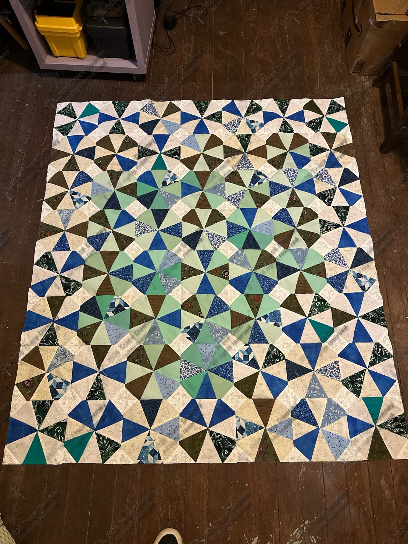 Cool-toned geometric quilt in blue, green, black, and neutral fabrics.
