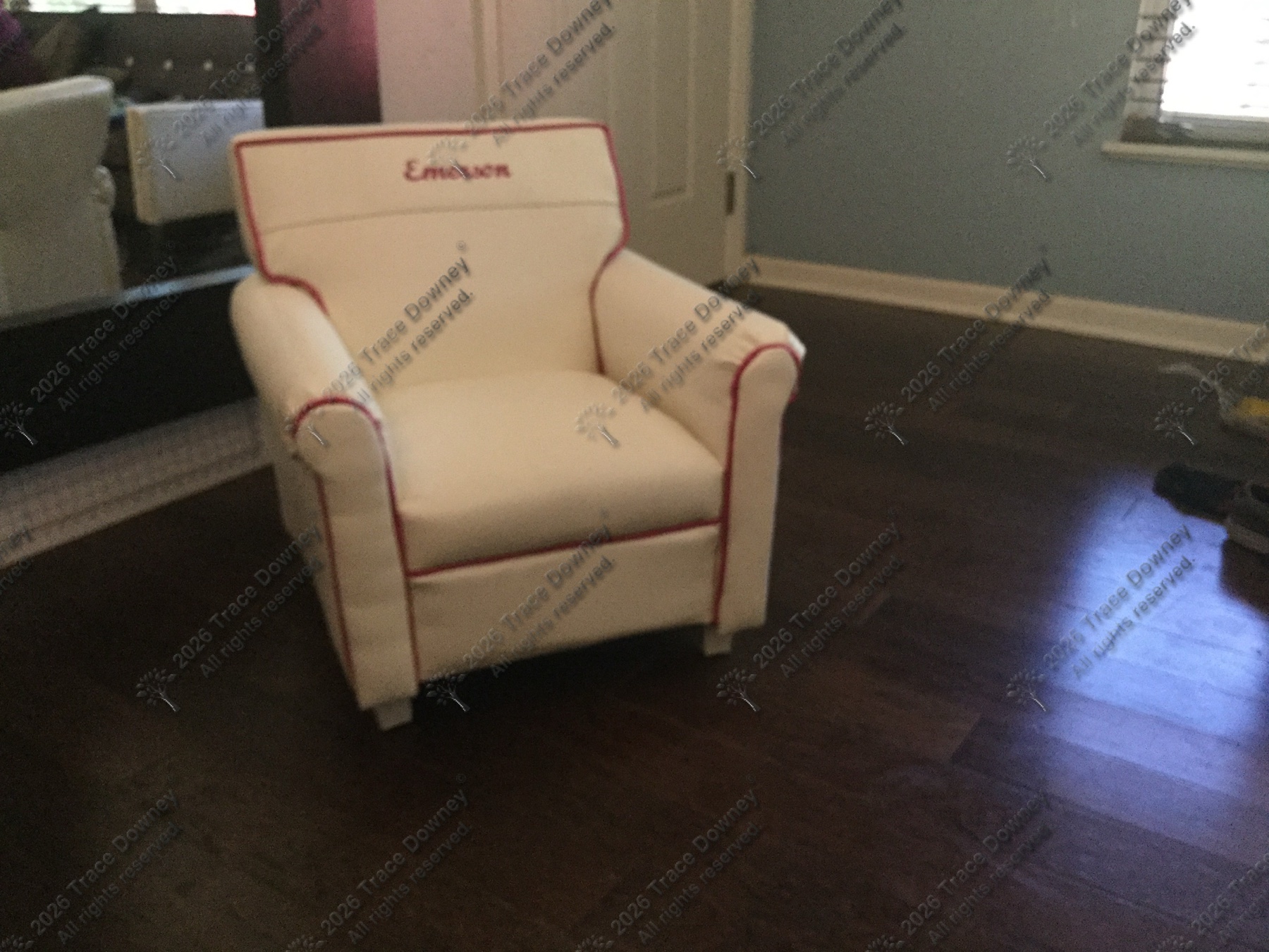 Finished white chair with red piping seen at an angle in a room.