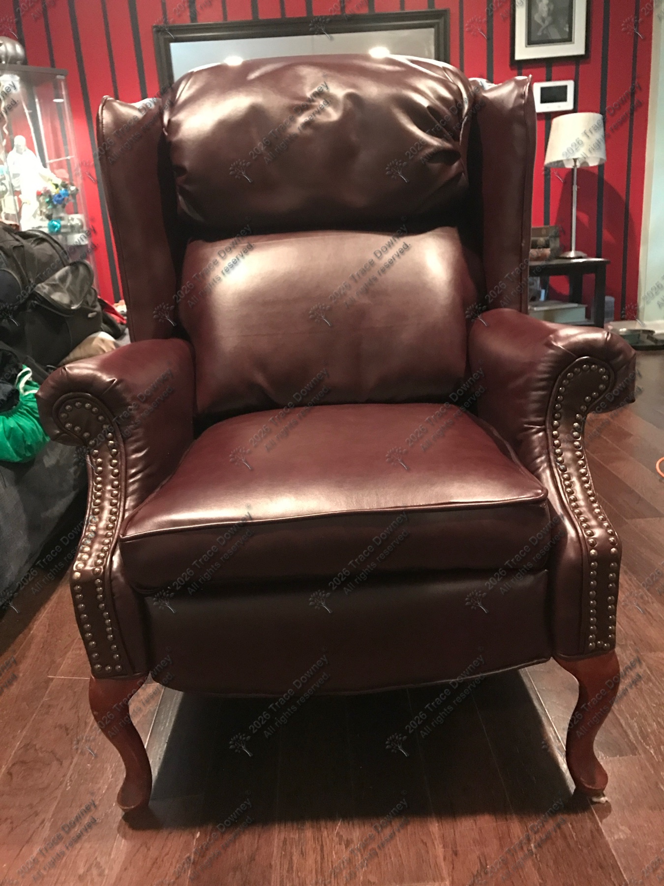 Finished burgundy leather wingback chair with nailhead trim.